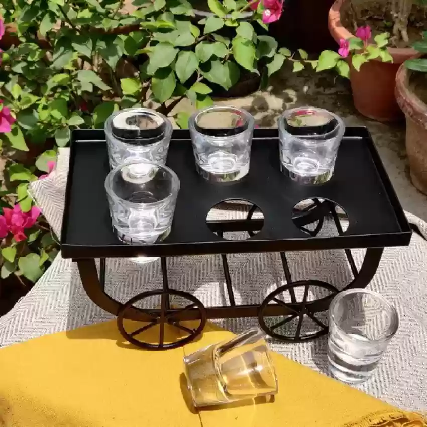 Wrought iron cart with 6 shot glasses in garden setting